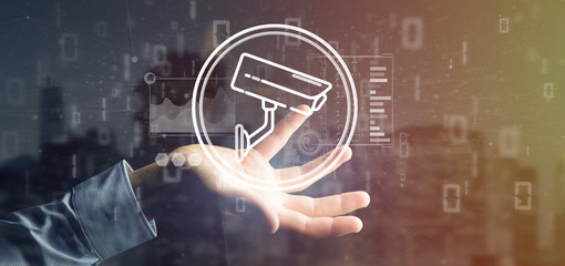 Poster - Businessman holding Security camera system icon and statistics data - 3d rendering