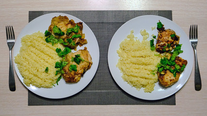 Pasta Orzo with grilled chicken. Macaroni in the form of rice with meat and herbs. Pasta on a plate with fried chicken sprinkled with parsley. Two servings and forks for left-handed and right-handed.