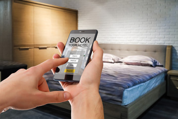 holding a smartphone with booking hotel room app on screen for make reservation