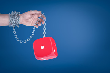 Poster - male hand chained to red dice on blue background