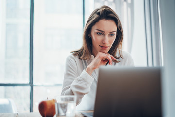 Confident business female using mobile laptop for looking a new business solution during work process at office.Blurred background