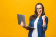 © denis_vermenko - Successful woman with a laptop computer and arms up - isolated over yellow