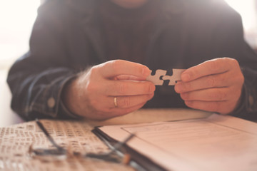 Business senior man assembling pieces of a puzzle.