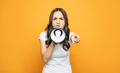 Wall Mural - Healthy yells. An angry girl with a speaking-trumpet in her one hand is screaming on somebody and pointing out right on this person.