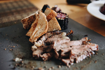 Blurred roast beef, corn, bread served on the table.