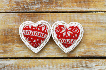 Two red knitted hearts on rustic wooden surface