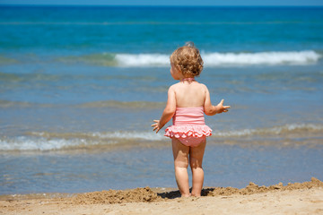 Child playing on tropical beach. Little girl digging sand at sea shore. Travel with young children