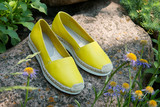 Fototapeta  - Yellow espadrilles close up. Summer footwear.  Yellow espadrilles in nature. A pair of espadrilles on stone.