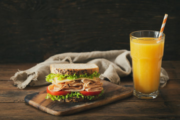 sandwich with ham and glass of orange juice