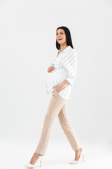 Sticker - Full length photo of pleased pregnant businesswoman 30s smiling and touching her big tummy