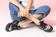 Woman in stylish shoes sitting on color background, closeup