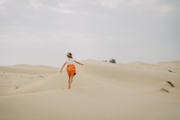 Little girl walks in sand dunes