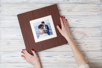 brown photo book with leather cover. stylish wedding photo album. a person opens a photobook. family