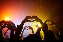 Crowd Of Unrecognizable Fans Joining Hands In Shape Of Hearts While Expressing Love In Relation To Performer At Concert