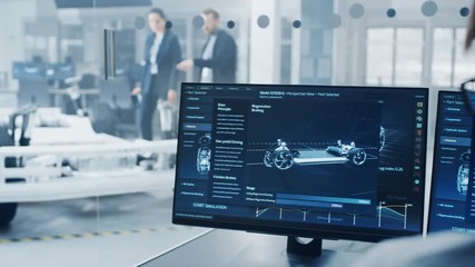 Fototapete - Professional Engineer Works on a Computer with a 3D CAD Software and Tests the Electric Car Chassis Prototype with Wheels, Batteries and Engine Standing in a High Tech Development Laboratory.