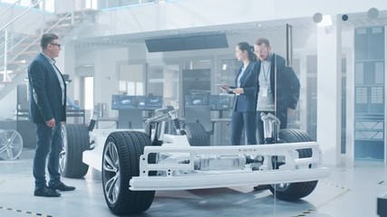 Fototapete - Automotive Design Engineers Talking while Working on Electric Car Chassis Prototype. In Innovation Laboratory Facility Concept Vehicle Frame Includes Wheels, Suspension, Engine and Battery.