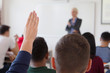 © as-artmedia - Group of university  students sitting at classroom and holding hand up. Interact with female attractive professor in the classroom. University student being helped by female lecturer during class.
