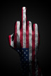 A hand with a drawn USA flag shows the middle finger, a sign of aggression, on a dark background