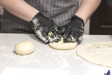 Baking concept. Hard working women prepares pastry by himself, kneads dough on wooden counter with flour and rolling pin. Women cook bakes bread or delicious bun or pasta