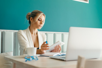 Beautiful girl working out a plan of the project and concept. Girl paints a website design on a laptop. student prints a message on the phone in the messenger. Development. Digital marketing