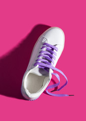 Wall Mural - White sneaker with purple laces on pink background. Shadow. Modern minimal fashion art trendy bold color flat lay