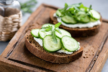 Rye Bread With Cream Cheese And Cucumber On Wooden Cutting Board. Closeup View, Selective Focus, Horizontal Orientation