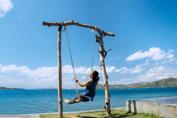 Sticker - Young woman enjoys seascape on the swing