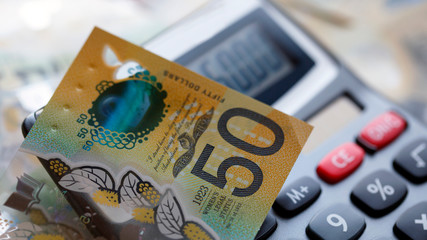 Wall Mural - Australian fifty dollar bill over a calculator. The new 2019 issue is designed to deter counterfeiting, the note is polymer and water resistant with a clear holographic strip