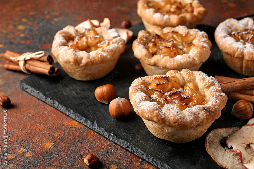Slate plate with tasty apple pies on table