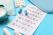 © Pixel-Shot - Menstrual calendar with feminine products and pills on color background