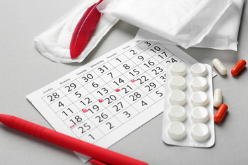 Sticker - Menstrual calendar with feminine products and pills on grey background