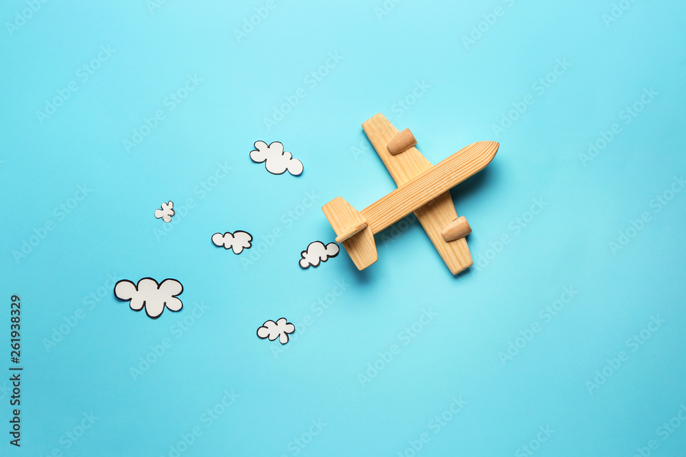 Toy airplane and paper clouds on color background. Travel concept