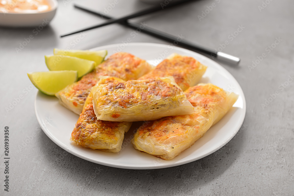 Plate with tasty fried spring rolls on table