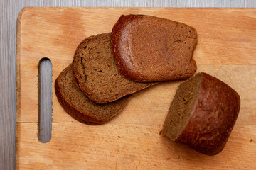 Wall Mural - slices of brown baked bread on wooden cutting board