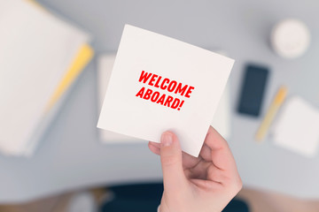 Wall Mural - Woman clerk sitting holding note paper sticker with welcome aboard phrase. Business concept. Concept.