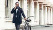 © Prostock-studio - African-american businessman talking on phone, riding bicycle