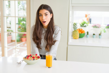 Poster - Young woman eating healthy breakfast in the morning afraid and shocked with surprise expression, fear and excited face.