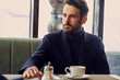 Thinking handsome man sitting in cafe and drinking cup of coffee on the breakfast. Closeup portrait