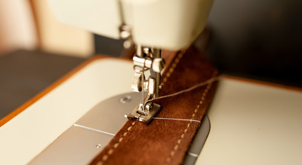 Background type of sewing machine, leather belt sewing process. Leather workshop.