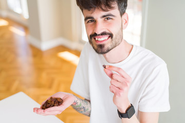 Wall Mural - Young man eating raisings, close up of hand with a bunch of healthy dry grapes