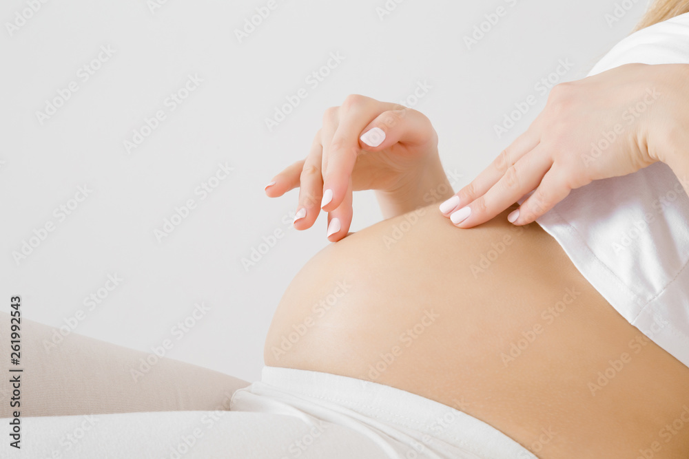 Woman lying down or sitting and touching belly with hand fingers. Emotional loving pregnancy time - 25 weeks. Baby expectation. Love, happiness and safety concept. Gray background. Closeup. Side view. - obrazy, fototapety, plakaty 