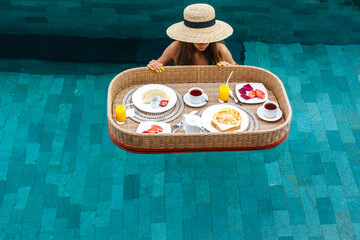 Girl eating floating breakfast in luxury hotel pool