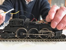 A Man Examines The Electrics And Wiring Of A Model Steam Engine.