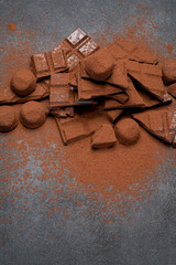 Wall Mural - Dark or milk organic chocolate pieces, cocoa powder and truffle candies on dark concrete backgound