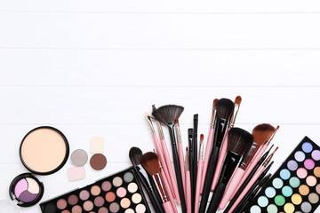 Makeup brushes with palette on white wooden table