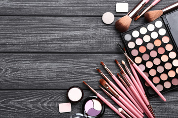 Makeup brushes with palette on black wooden table