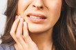 © denis_vermenko - Young European woman isolated on white background suffering from severe toothache, feeling pain so strong that she is pressing fingers to cheek to calm it down, looking desperate.