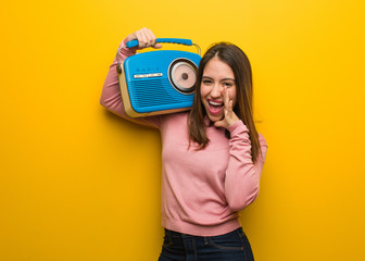 Young cute woman holding a vintage radio shouting something happy to the front