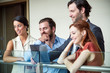 © PhotoAlto - Smiling business people standing with laptop on hotel balcony