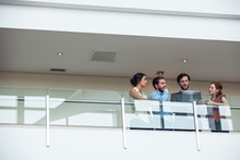 Businessmen And Businesswomen Using Laptop On Hotel Balcony